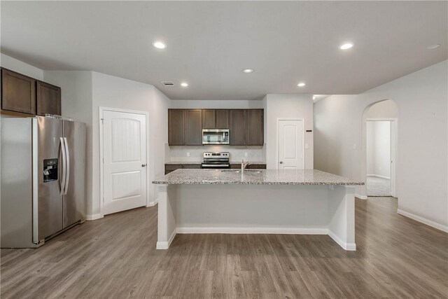 4706 Coyotillo Way, Bryan, TX 77807 - kitchen with stainless steel appliances, arched walkways, wood finished floors, dark brown cabinetry, and recessed lighting
