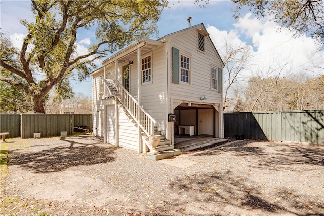 view of home's exterior with stairs, an attached garage, fence, and driveway