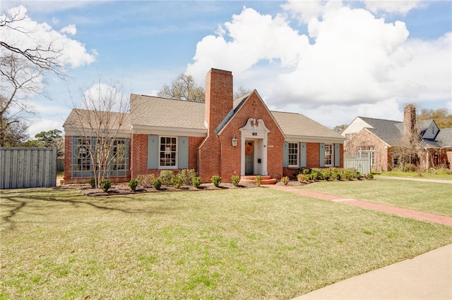 view of front of property with a front yard, fence, roof with shingles, a chimney, and brick siding