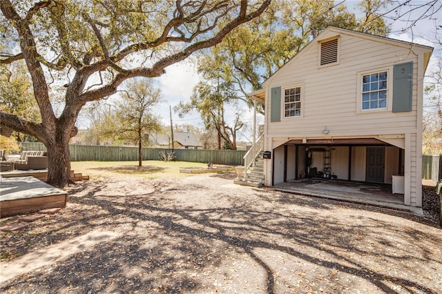 view of side of home featuring stairs, a patio, fence, and driveway