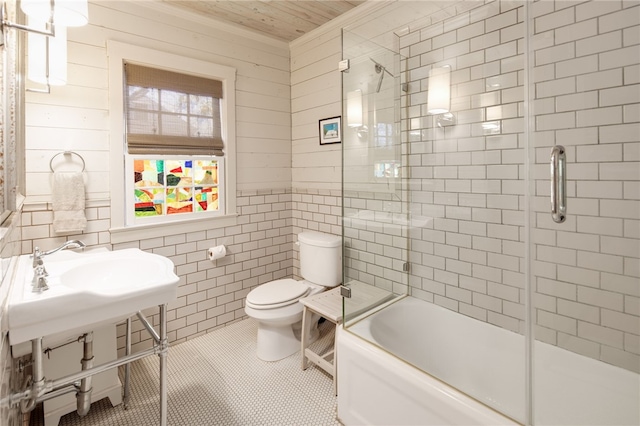 bathroom with enclosed tub / shower combo, toilet, tile walls, and tile patterned flooring