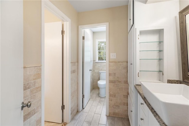 bathroom with vanity, tile walls, and toilet