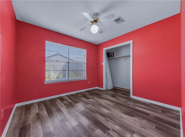 unfurnished bedroom featuring dark hardwood / wood-style flooring, ceiling fan, and a closet