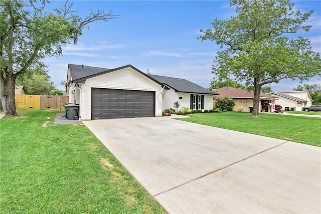 view of front of home featuring an attached garage, driveway, fence, and a front yard