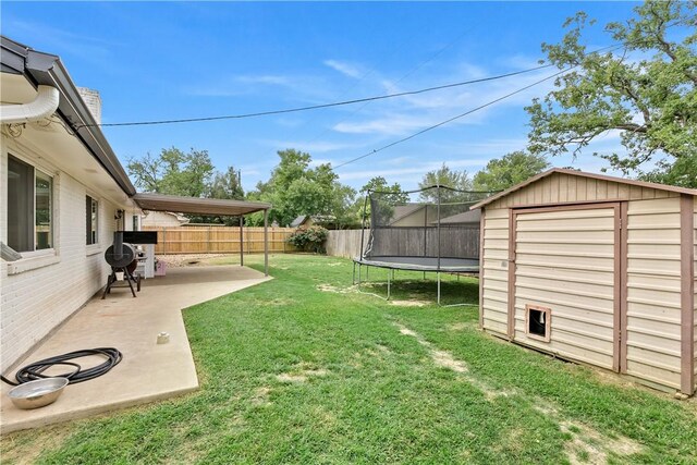 view of yard featuring a storage unit, an outbuilding, a fenced backyard, a trampoline, and a patio area