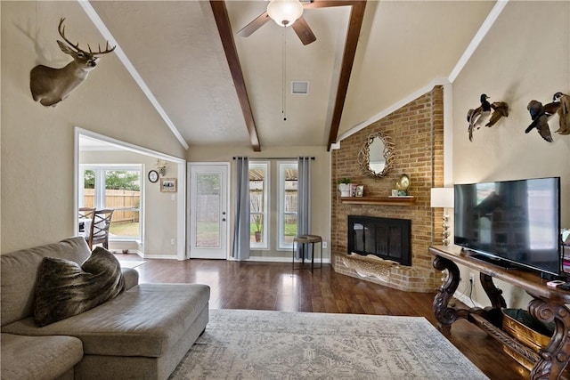 living area featuring a ceiling fan, wood finished floors, lofted ceiling with beams, baseboards, and a brick fireplace
