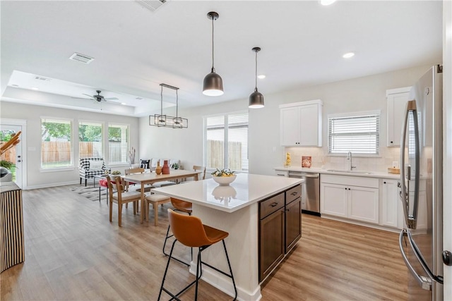 kitchen featuring stainless steel appliances, sink, a kitchen island, and white cabinets