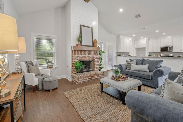 9868 Albert Dr, Iola, TX 77861 - living area with high vaulted ceiling, wood finished floors, a brick fireplace, and recessed lighting