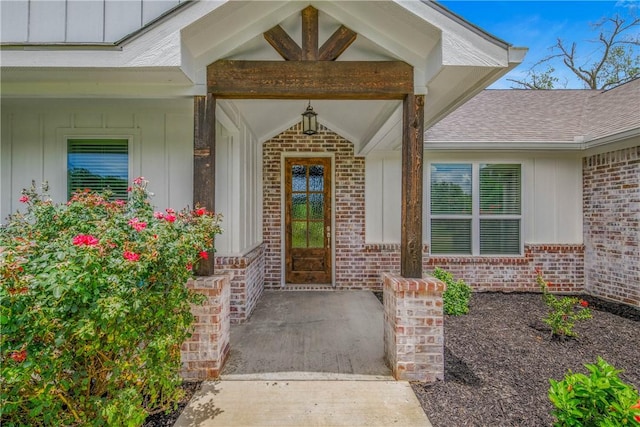 9868 Albert Dr, Iola, TX 77861 - view of exterior entry featuring board and batten siding, brick siding, and a shingled roof
