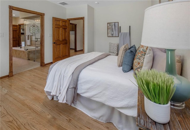 bedroom with light wood-type flooring and ensuite bath