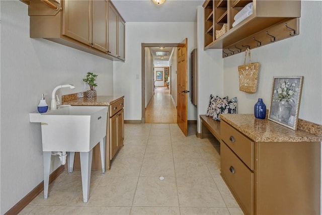 kitchen with light stone countertops, sink, and light tile patterned floors