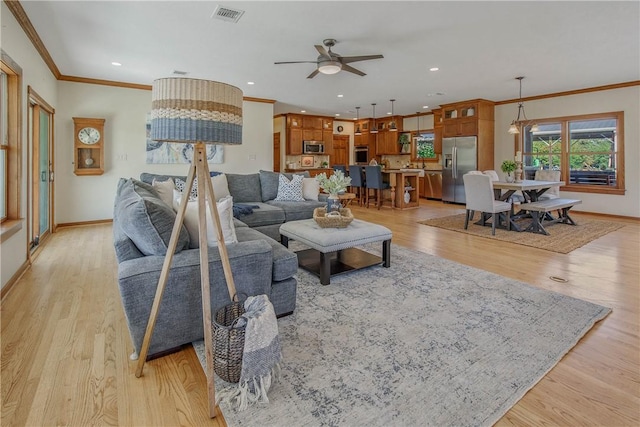 living room featuring crown molding, light hardwood / wood-style floors, and ceiling fan with notable chandelier