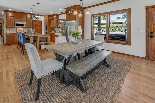 dining area with light wood-type flooring and ornamental molding