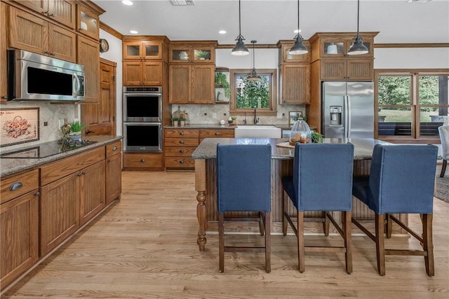 kitchen featuring a center island, dark stone counters, decorative light fixtures, a kitchen bar, and stainless steel appliances