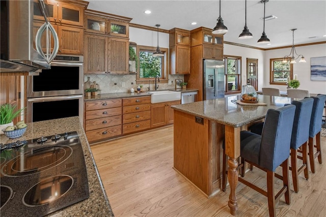 kitchen featuring appliances with stainless steel finishes, light wood-type flooring, ornamental molding, and sink