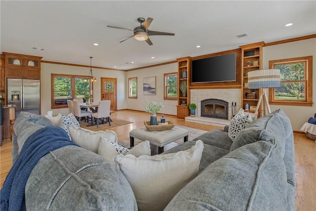 living room with ceiling fan, light hardwood / wood-style floors, ornamental molding, and a fireplace