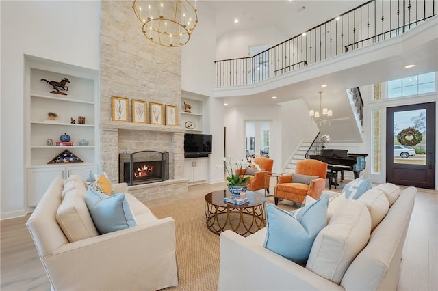 living area with a stone fireplace, stairway, a wealth of natural light, and an inviting chandelier