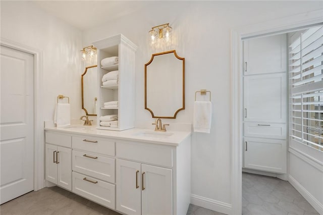 bathroom with double vanity, baseboards, and a sink