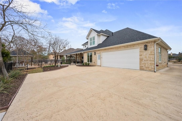 view of home's exterior featuring a garage, concrete driveway, fence, and a shingled roof