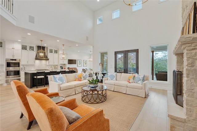 living area featuring light wood-style floors, plenty of natural light, a fireplace, and french doors