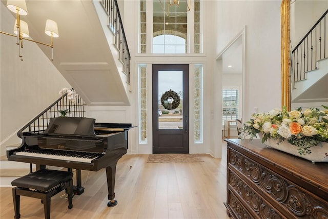 entryway with light wood-type flooring, stairway, and a high ceiling