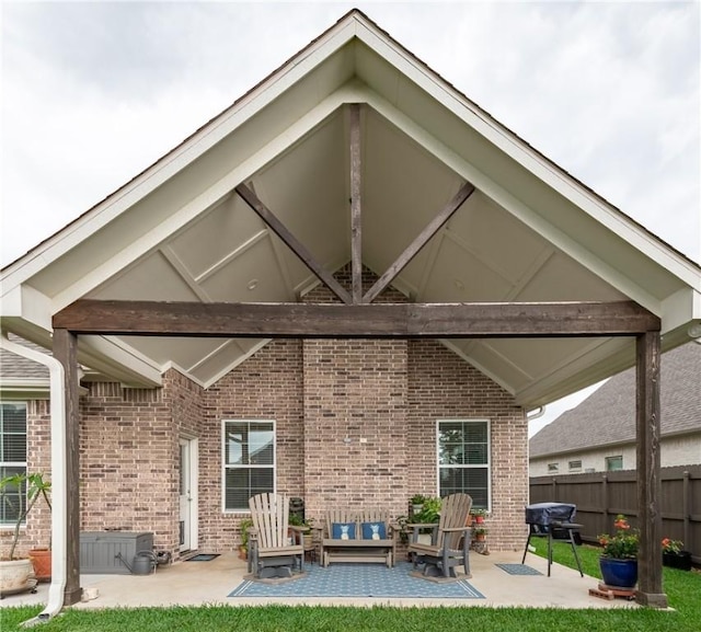 rear view of house featuring a patio, an outdoor living space, fence, and brick siding