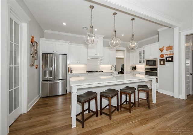 kitchen with white cabinets, appliances with stainless steel finishes, ornamental molding, and a sink
