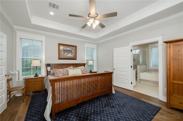 bedroom with crown molding, visible vents, wood finished floors, and a raised ceiling