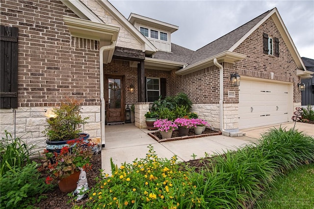 entrance to property featuring brick siding, driveway, a shingled roof, and a garage