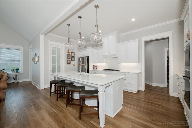 kitchen featuring light countertops, baseboards, a center island with sink, and a kitchen bar
