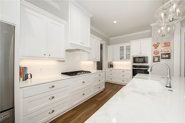 kitchen with dark wood-style flooring, appliances with stainless steel finishes, a sink, light countertops, and white cabinetry