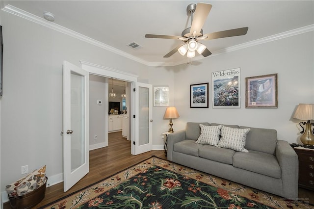 living room with a ceiling fan, visible vents, crown molding, wood finished floors, and baseboards