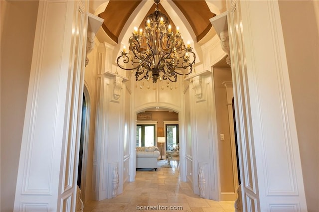 corridor with high vaulted ceiling and a notable chandelier