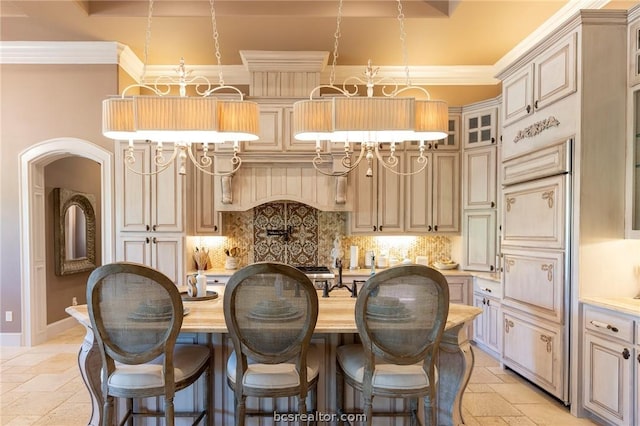 kitchen featuring tasteful backsplash, crown molding, a center island with sink, and pendant lighting