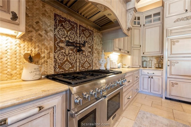 kitchen featuring backsplash, range with two ovens, and premium range hood