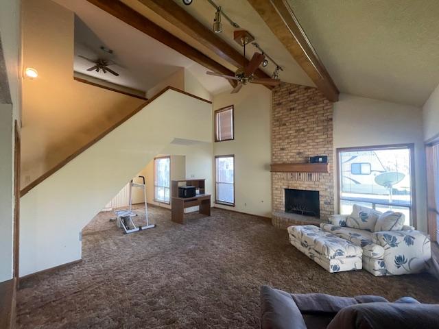 living area with a brick fireplace, plenty of natural light, and ceiling fan