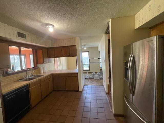 kitchen featuring dishwashing machine, stainless steel fridge, wallpapered walls, and a sink