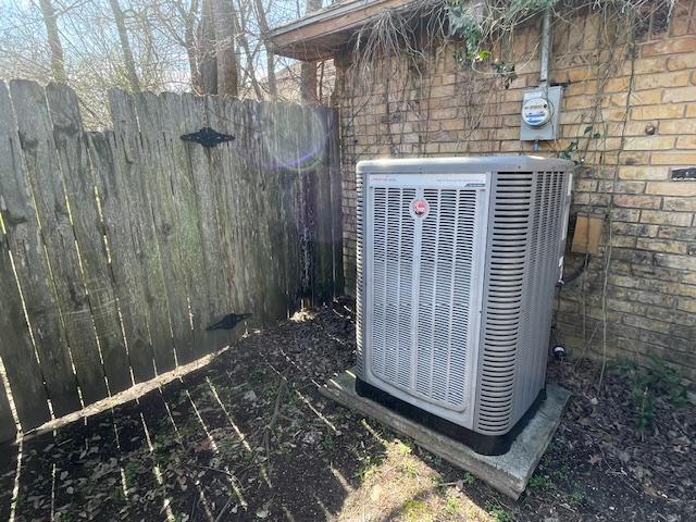 details featuring central AC unit, electric meter, and fence