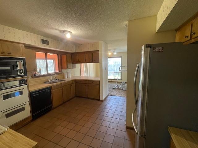 kitchen featuring visible vents, black appliances, light countertops, a textured ceiling, and a sink