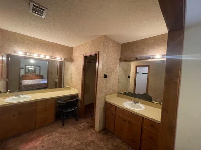 full bath featuring visible vents, a textured ceiling, and a sink