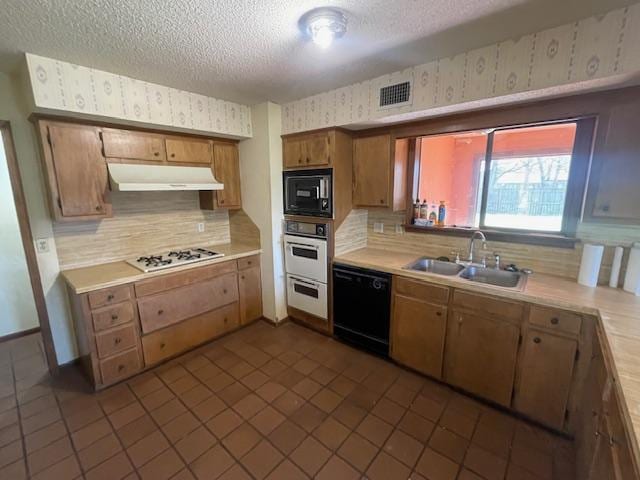 kitchen with visible vents, wallpapered walls, under cabinet range hood, black appliances, and a sink