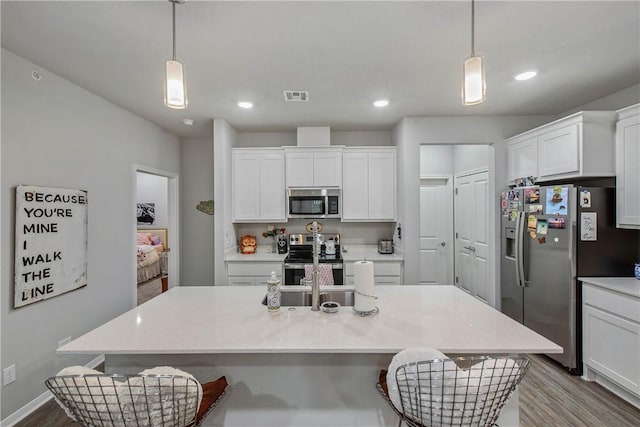 kitchen with stainless steel appliances, a breakfast bar, visible vents, and white cabinetry