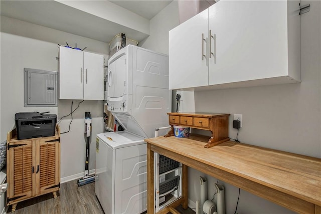 clothes washing area with stacked washer and dryer, electric panel, cabinet space, and wood finished floors