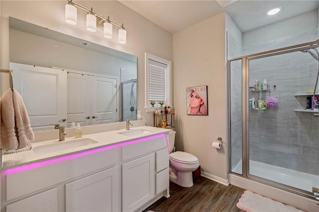 bathroom with double vanity, a stall shower, a sink, and wood finished floors