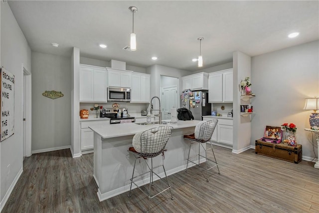 kitchen featuring appliances with stainless steel finishes, white cabinets, a sink, and wood finished floors