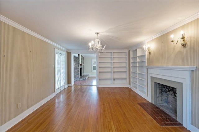 1712 Glade St, College Station, TX 77840 - unfurnished living room featuring a fireplace with raised hearth, a chandelier, wood finished floors, built in shelves, and ornamental molding