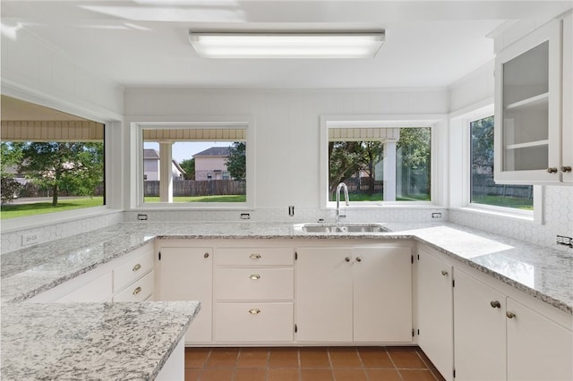 1712 Glade St, College Station, TX 77840 - kitchen featuring tile patterned flooring, light stone countertops, glass insert cabinets, and white cabinetry