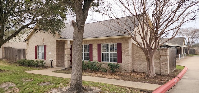 view of front of house with a shingled roof, fence, and brick siding