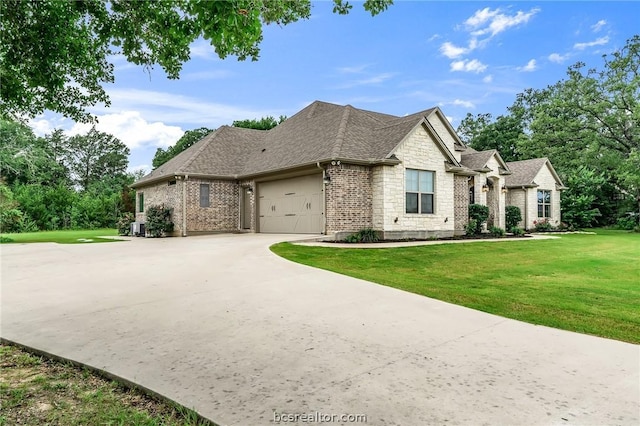 french country style house featuring a front lawn, central AC unit, and a garage