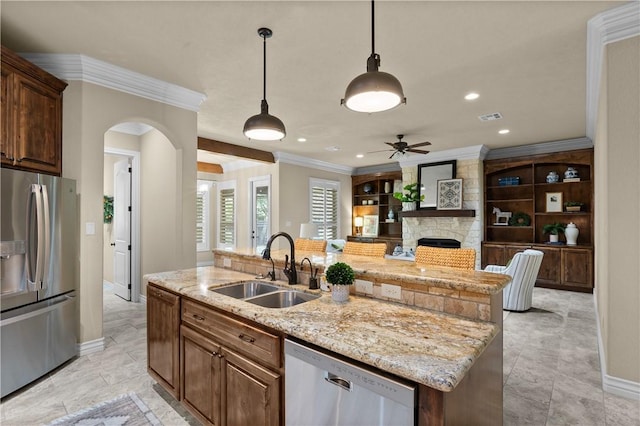 5104 Stonewater Loop, College Station, TX 77845 - kitchen featuring appliances with stainless steel finishes, crown molding, a fireplace, arched walkways, and an island with sink